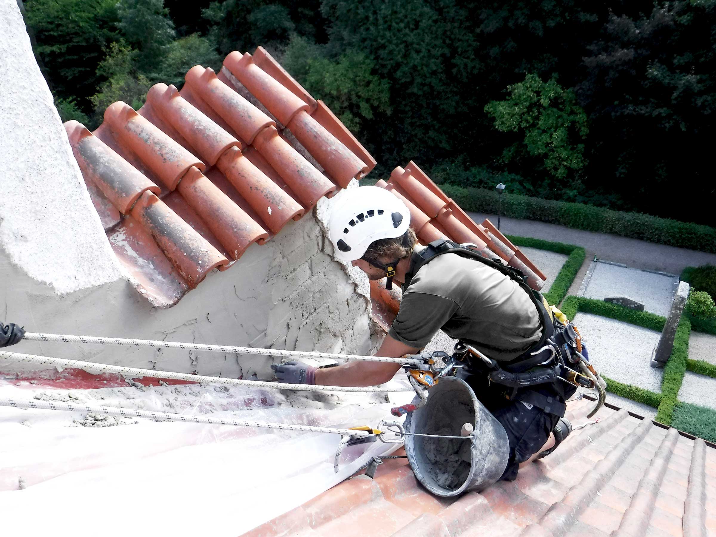 Man hängandes i sele och arbetar på fasad