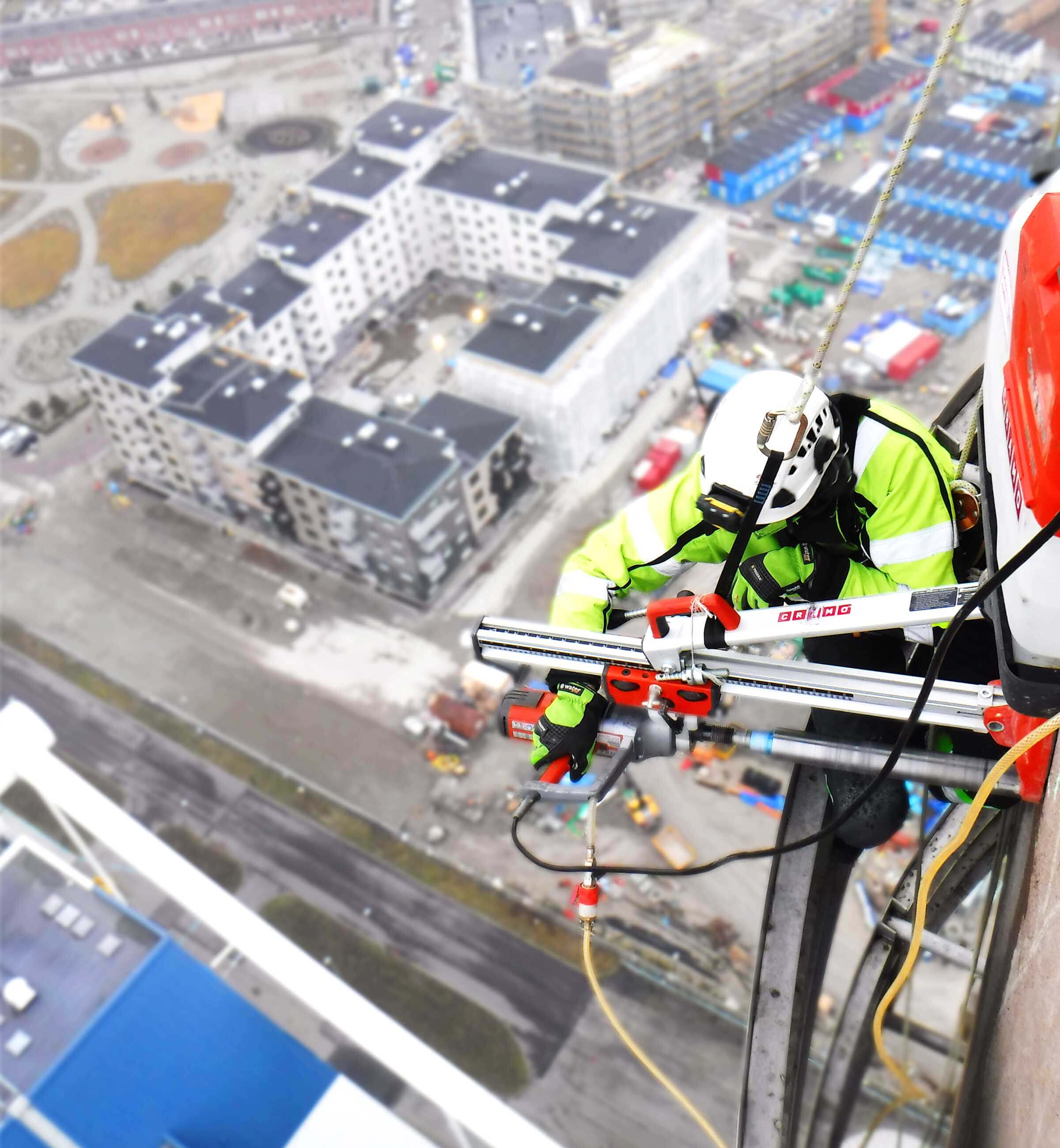 man hängandes i sele borrar i betong med betongborr