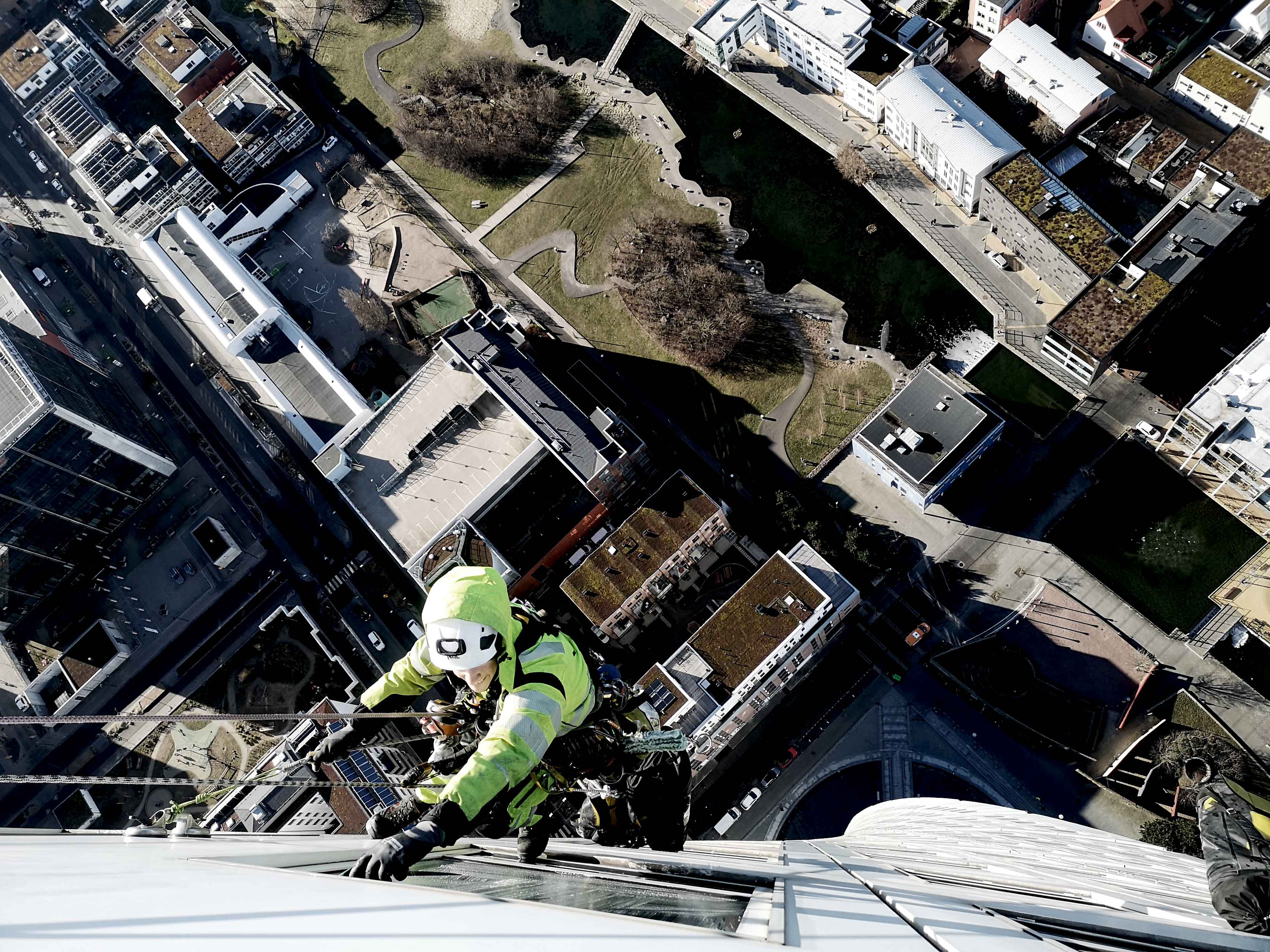 Man hängandes i skyskrapa och putsar fönster