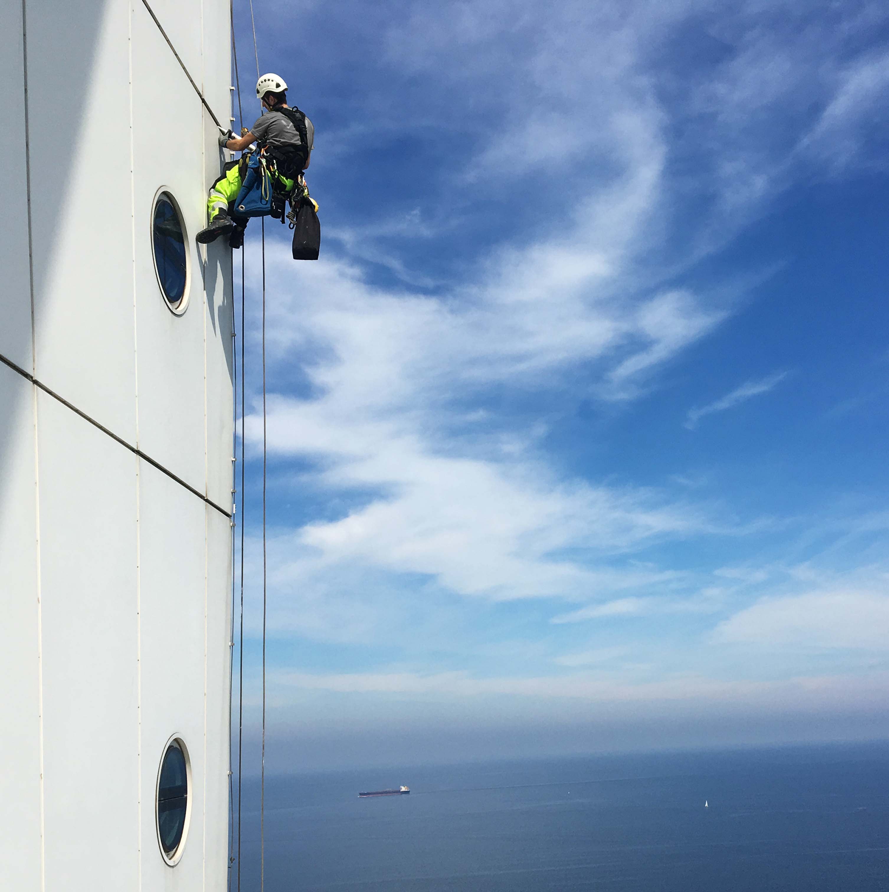 arbetare hängandes i sele och utför fogningsarbete på turning torso
