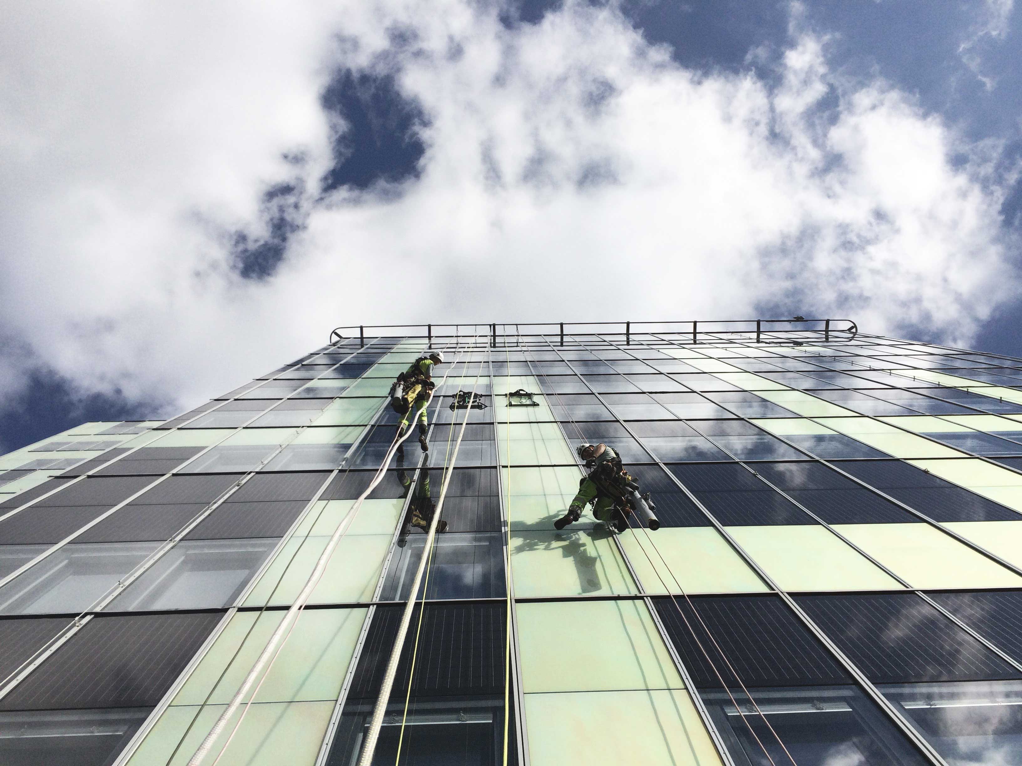 två personer hängandes i sele och utför glasmontage