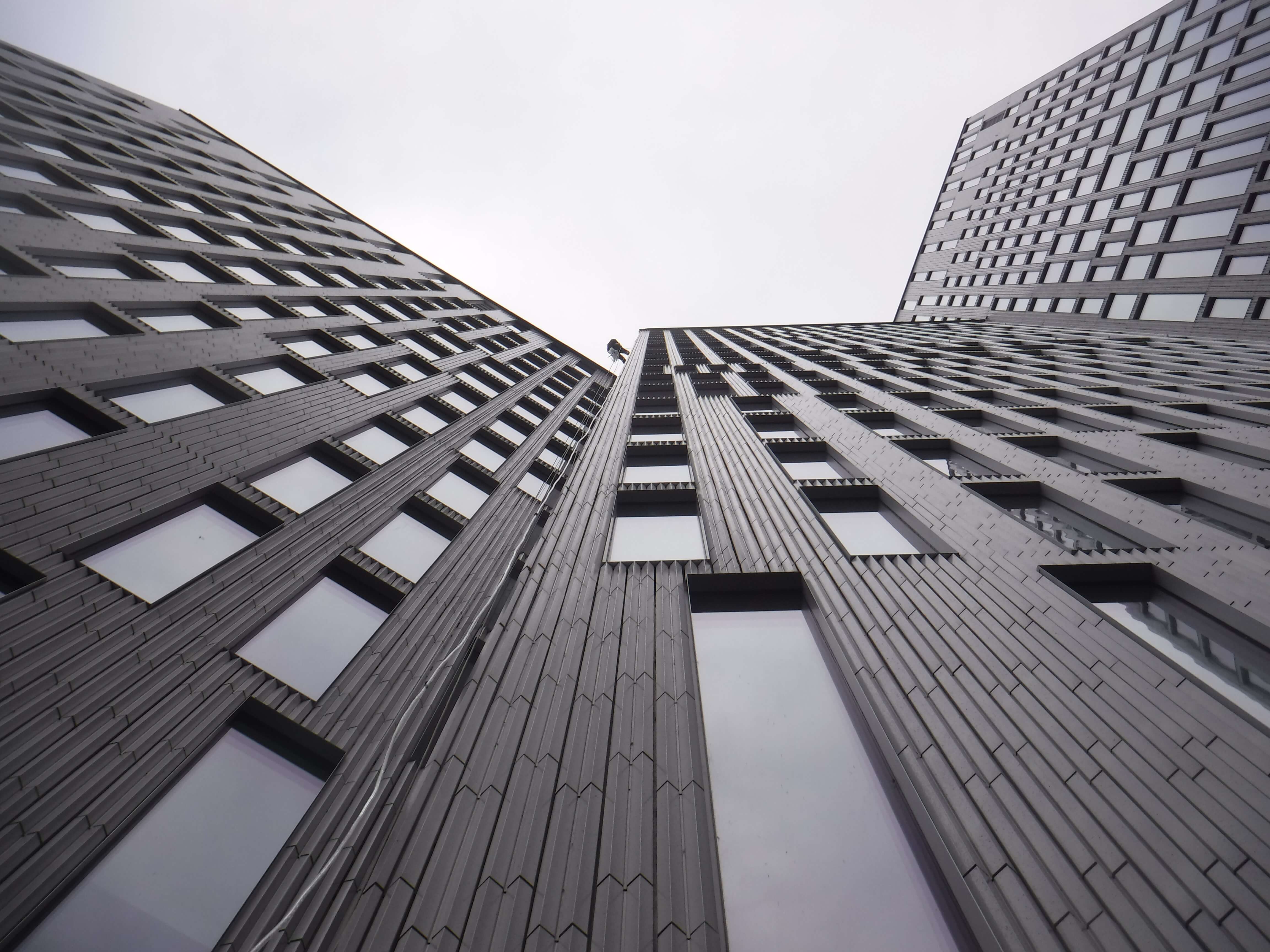 nyproducerad ny fastighet där en person hänger i sele och utför arbete