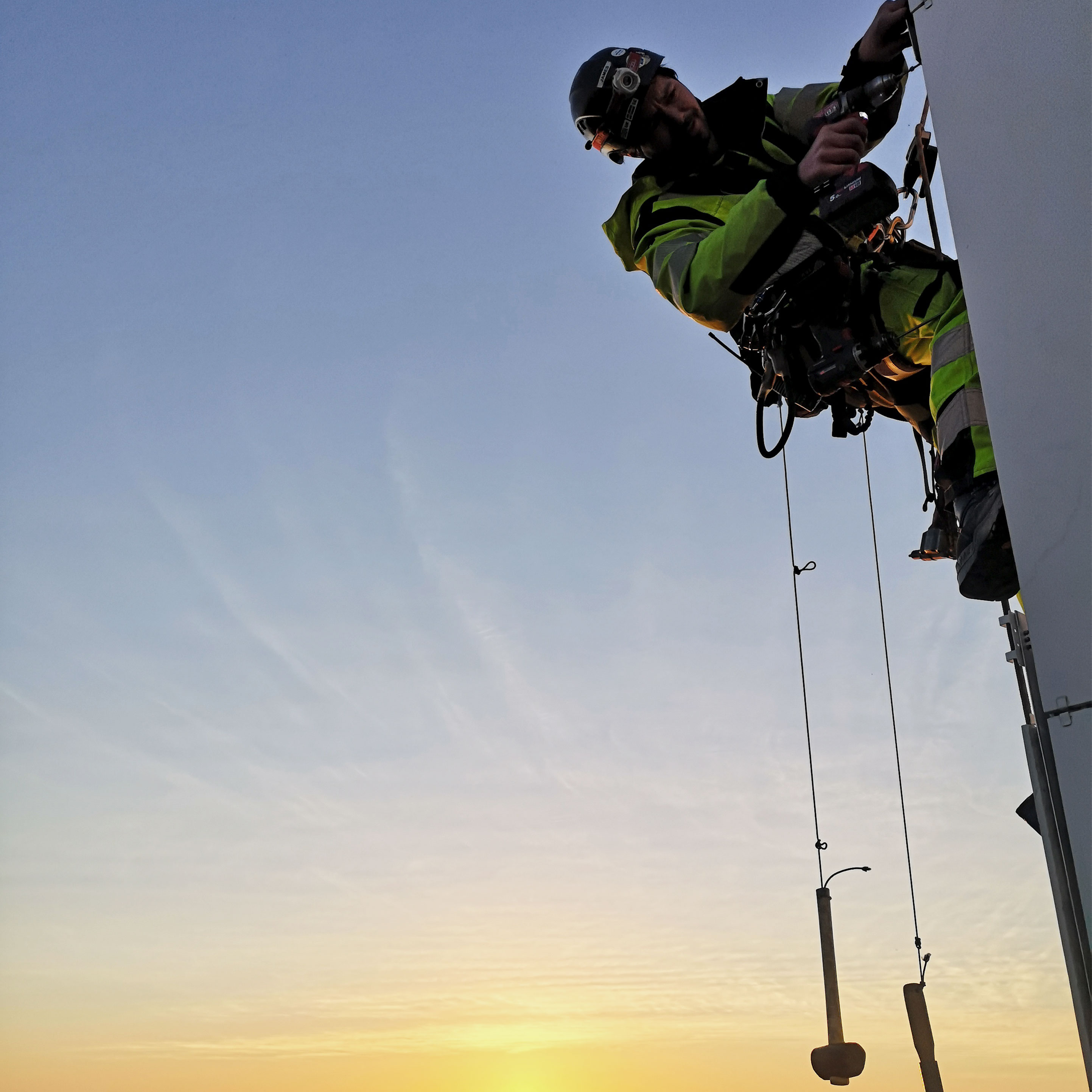 montage med skruvdragere av man hängandes i sele