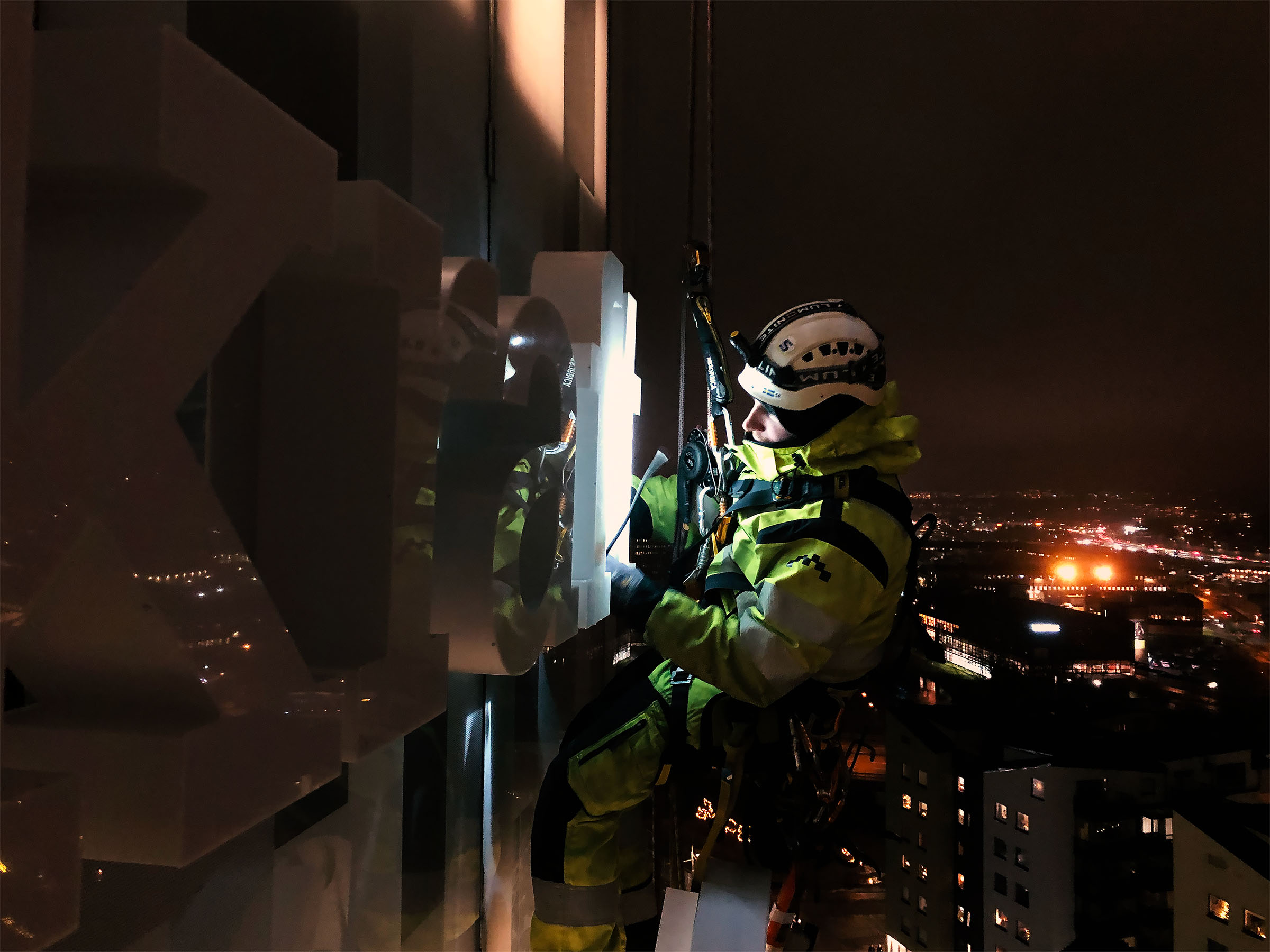 glasmontage av man hängandes i sele i mörker