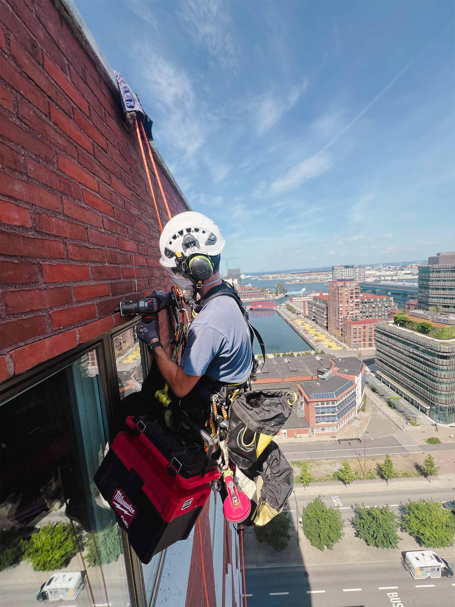 Man hängandes i sele och arbetar på fasad